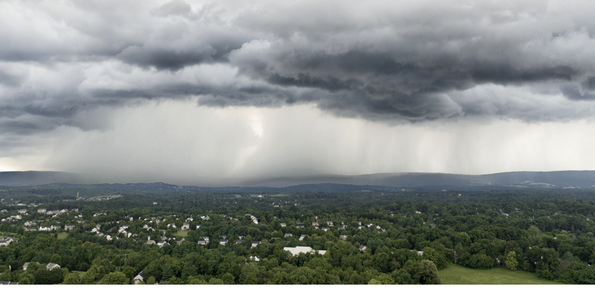 Storm clouds above a forested residential area